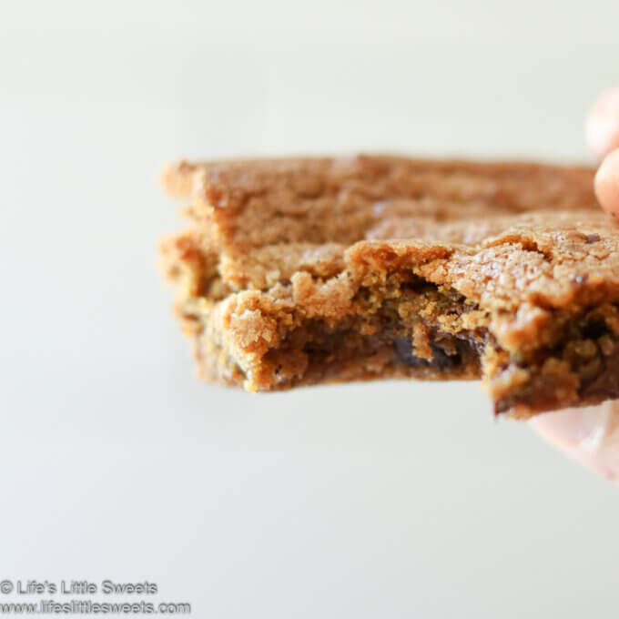 hand holding a Brown Butter Chocolate Chip Cookie Bar with a bite taken out of it