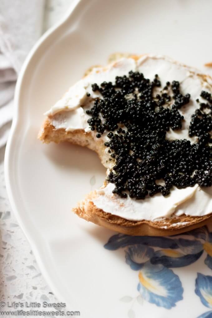 Caviar Cream Cheese Bagel with a bite taken out of it on a plate