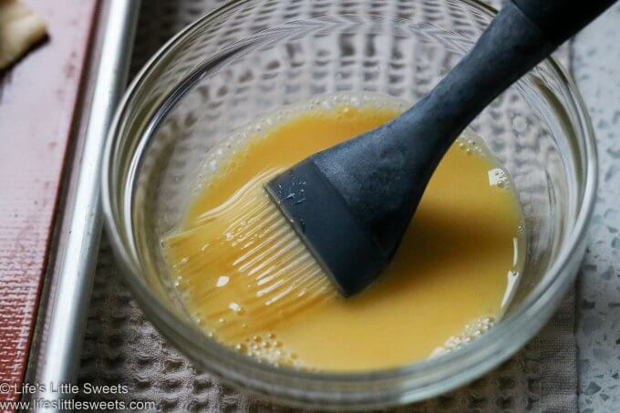 egg wash in a bowl with a silicone pastry brush