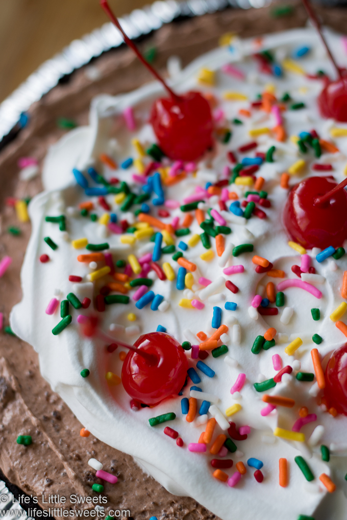 Up close vertical photo of Chocolate Pudding Pie with Cool Whip, color sprinkles and maraschino cherries