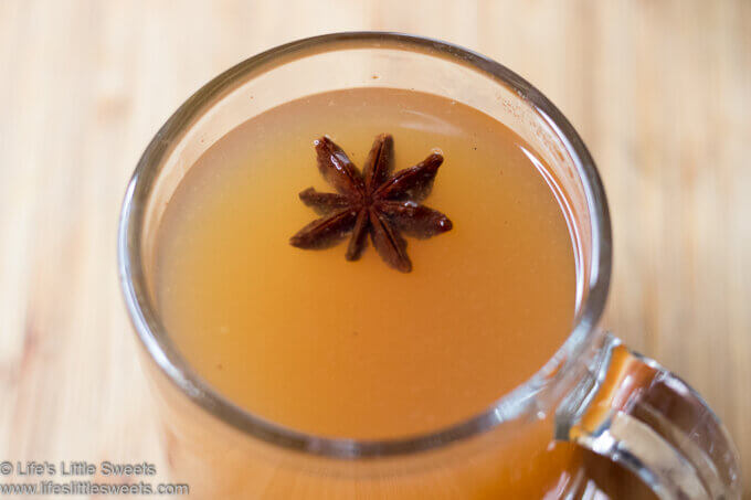 Hot Mulled Cider (Wassail) in a clear mug with star anise on a wood table