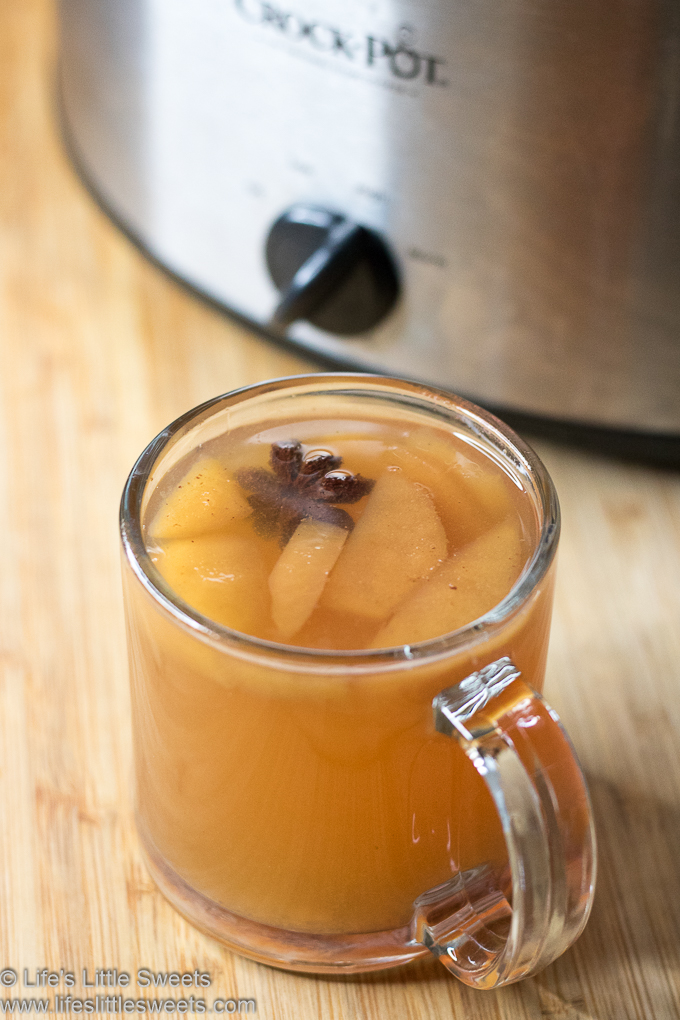 Hot Mulled Cider (Wassail) in a clear mug with star anise with a Crock Pot in the background