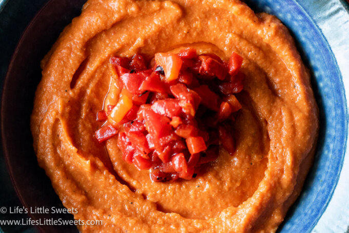 close up of roasted red pepper hummus in a blue bowl