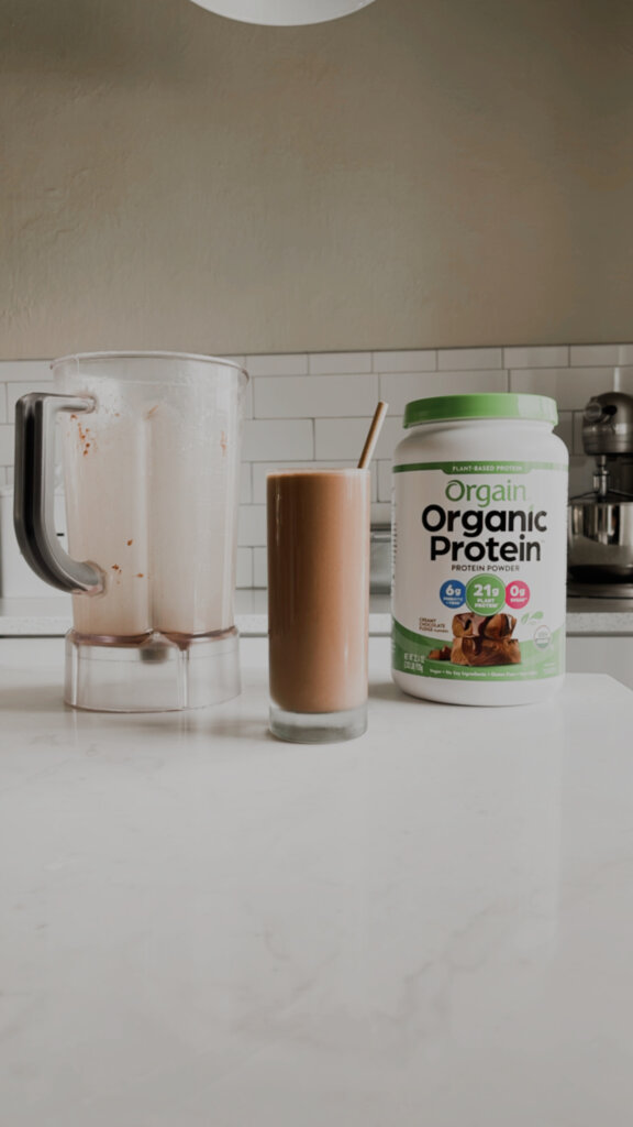 Chocolate Protein Drink Recipe in a white kitchen with protein powder and a blender