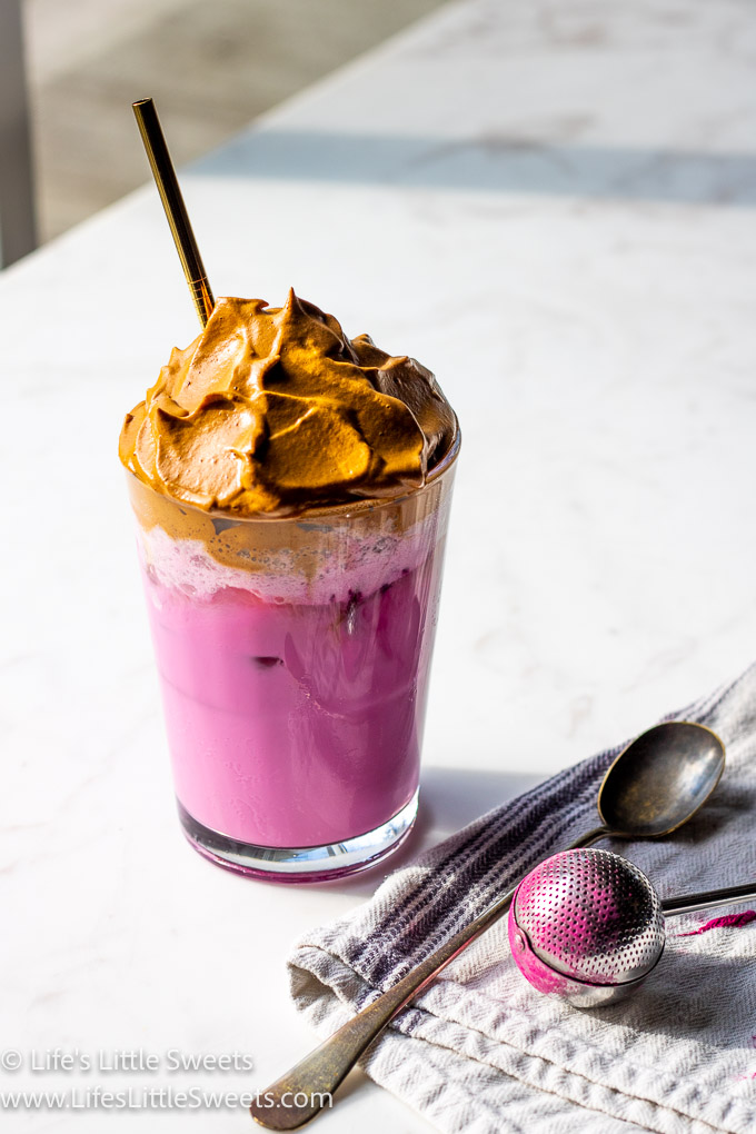 Dragon Fruit Whipped Coffee on a white marble countertop and a gold straw