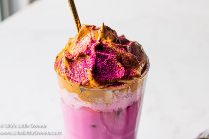 Dragon Fruit Whipped Coffee on a white marble countertop and a gold straw