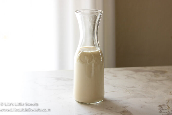 homemade oat milk in a glass milk bottle on a marble table
