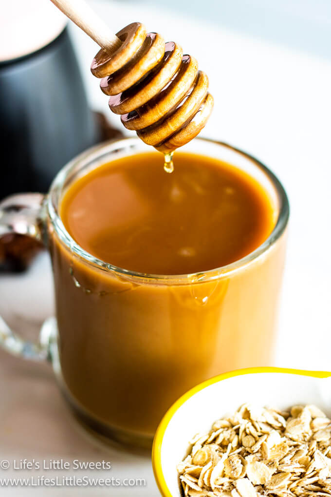 a honey dipper dripping wildflower into an oat milk latte