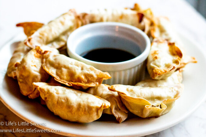 a white plate of air fried dumplings with soy sauce on a marble surface
