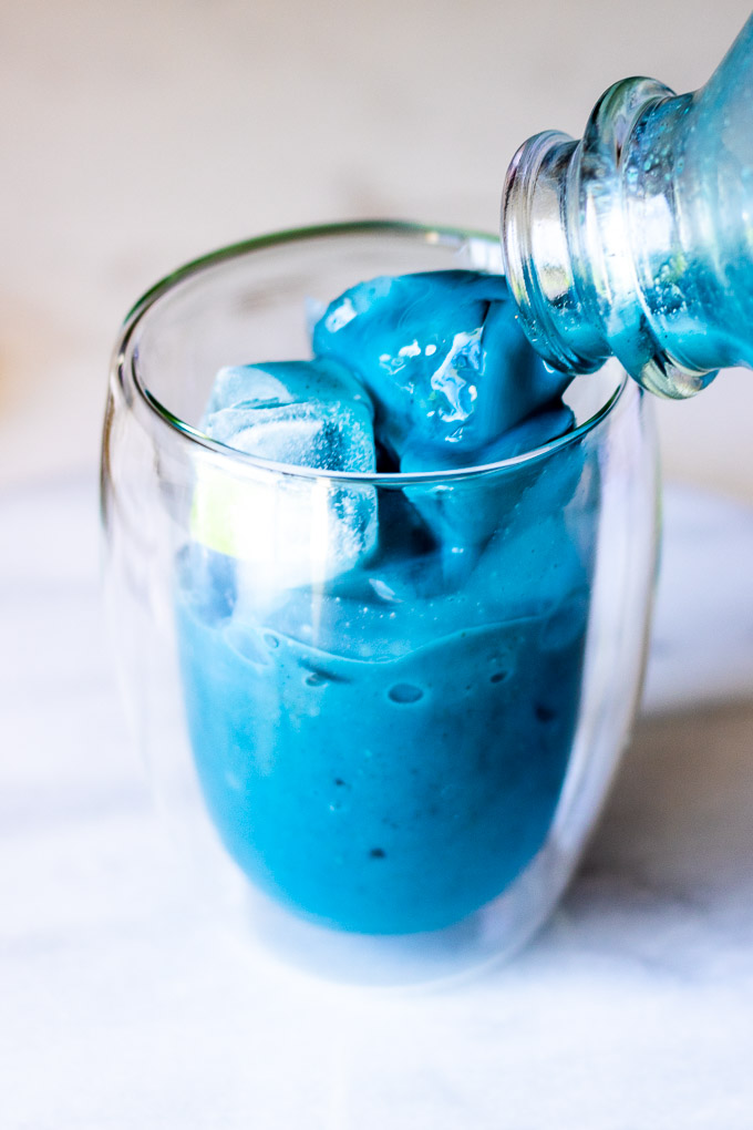 Butterfly Pea Flower Milk Tea overhead with ice on a white marble countertop