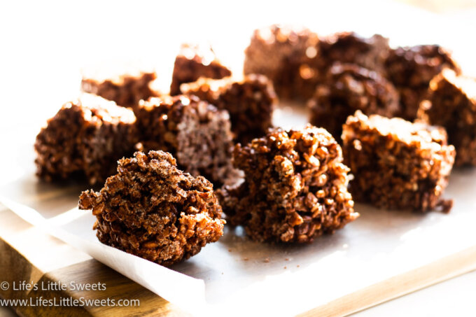 Chocolate Rice Krispie Treats on parchment paper over a wood cutting board