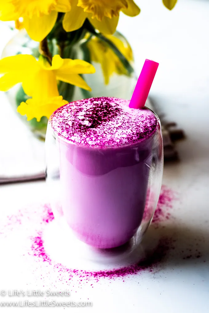 Dragon Fruit Steamed Milk with a pink straw and yellow daffodils