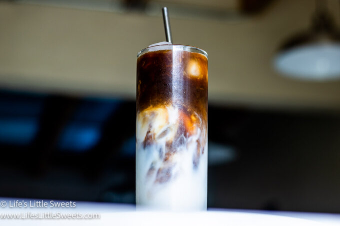 Iced Coffee with Almond Milk on a marble counter with a pendant light in the background
