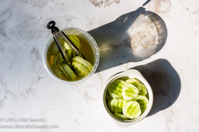 Cucumbers in Pickle Juice in 2 containers over a marble countertop
