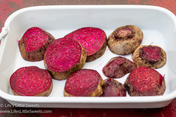 red, uncooked Beets in a white serving platter on a red metal table