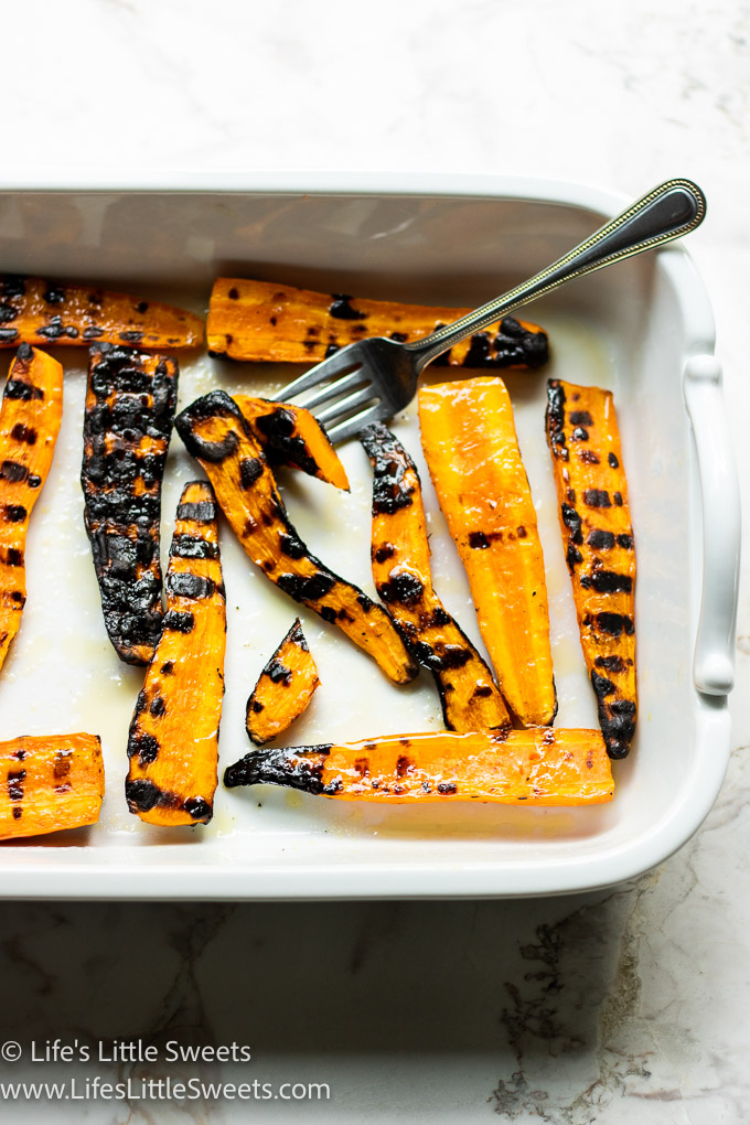grilled carrots with a fork in a white dish