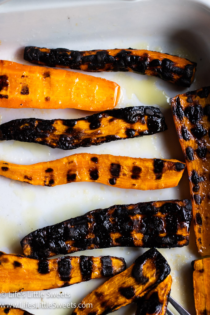 close up of grilled carrots in a white serving dish