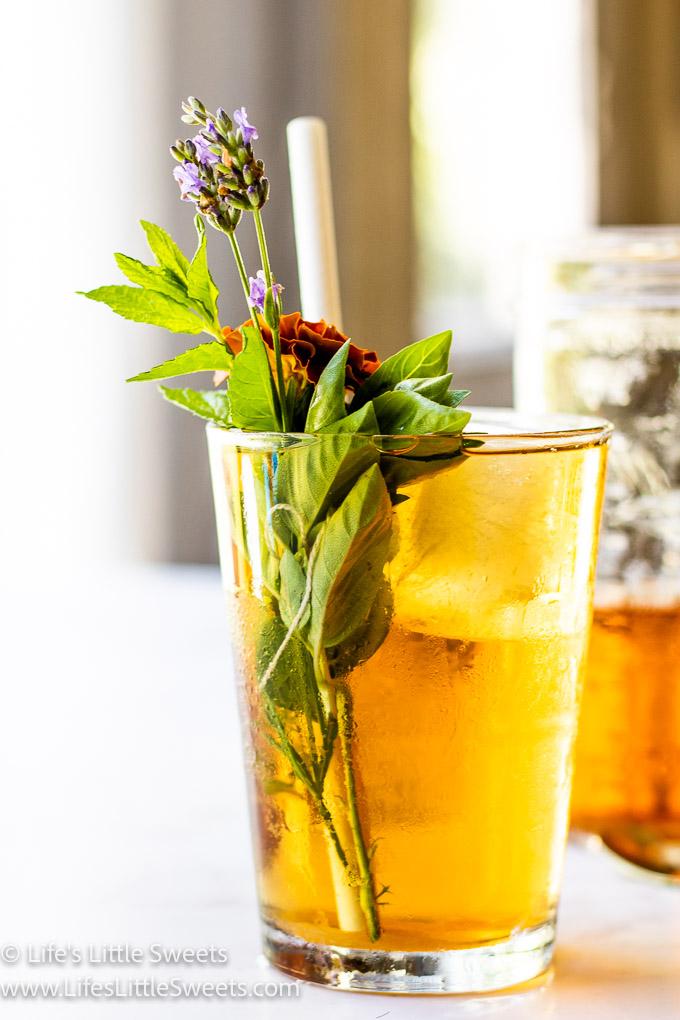 side view of iced tea with herbs on a white countertop