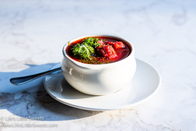 red Borscht soup with dill and sour cream on a marble table top