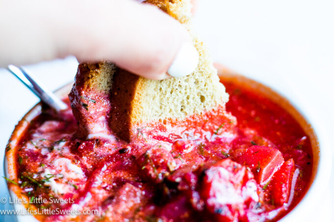 Rye bread dipping into a bowl of red Borscht soup
