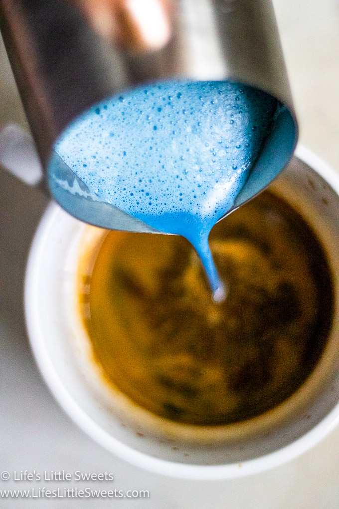 pouring blue steamed milk into espresso