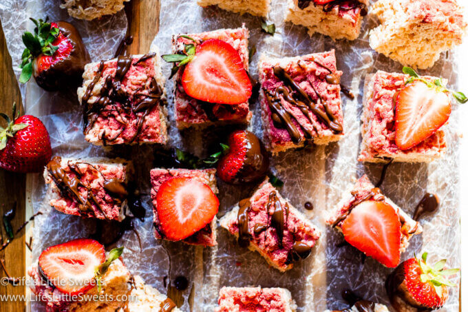 Strawberry Rice Krispie Treats with chocolate and fresh sliced strawberries on parchment paper over a wood surface