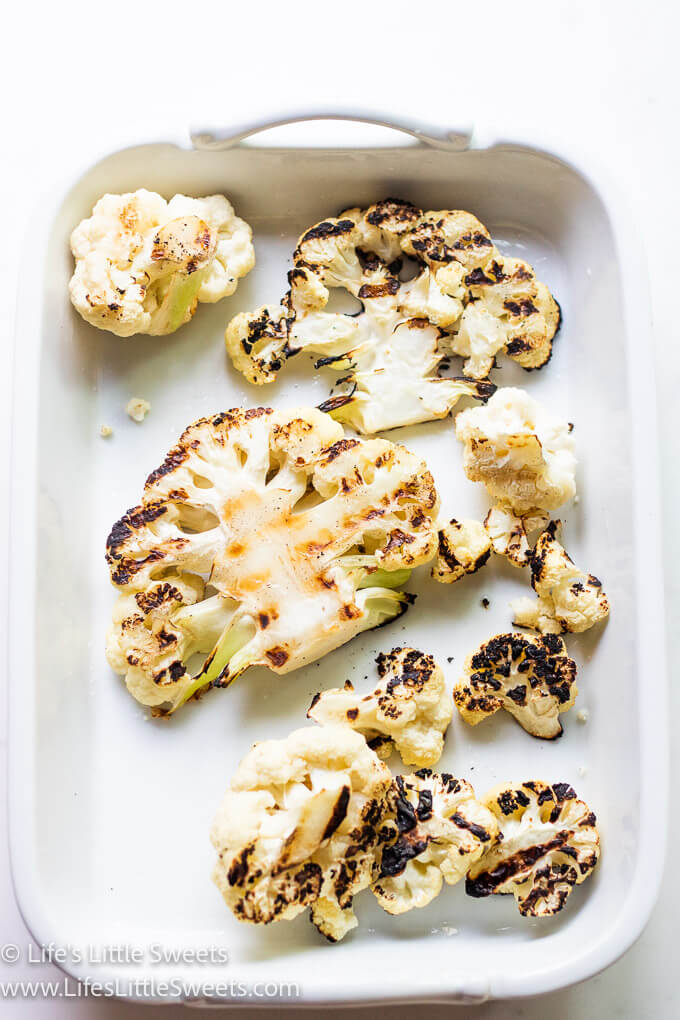 cooked cauliflower with grill marks in a white platter over a white background