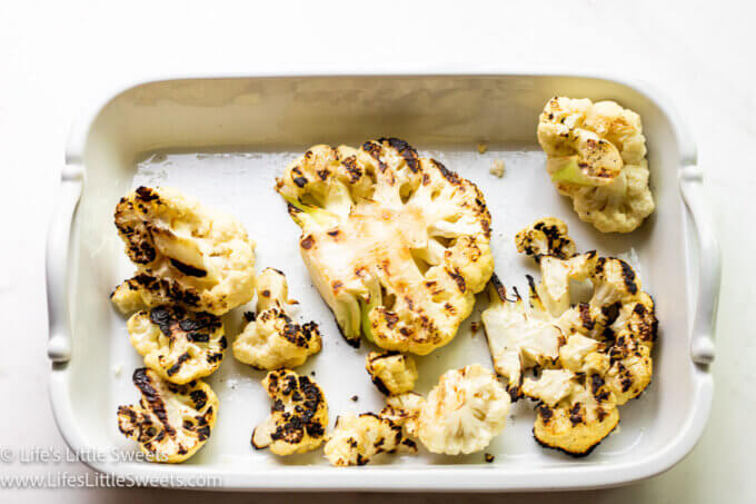 white cauliflower with grill marks in a white serving platter over a white marble table top