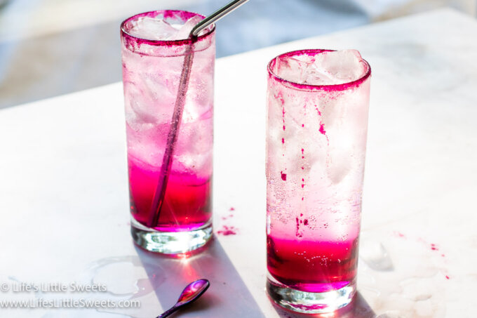 2 pink and clear cold drinks on a white table