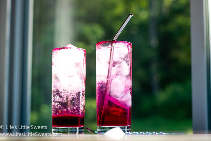 2 pink soda drinks on a white table near a window