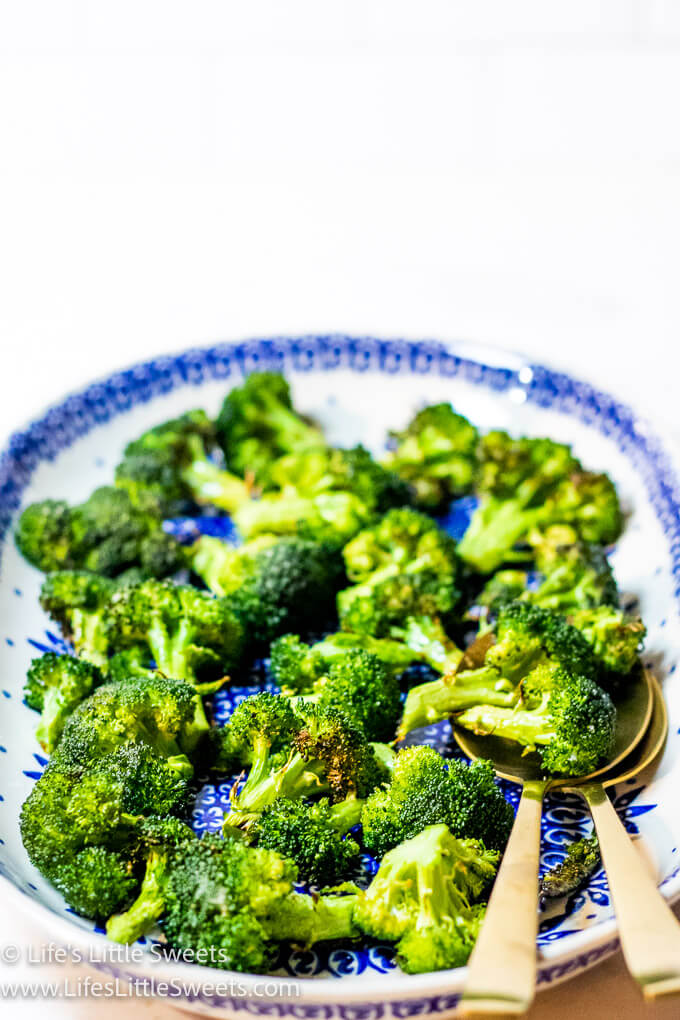 cooked broccoli on an oval plate with gold spoons