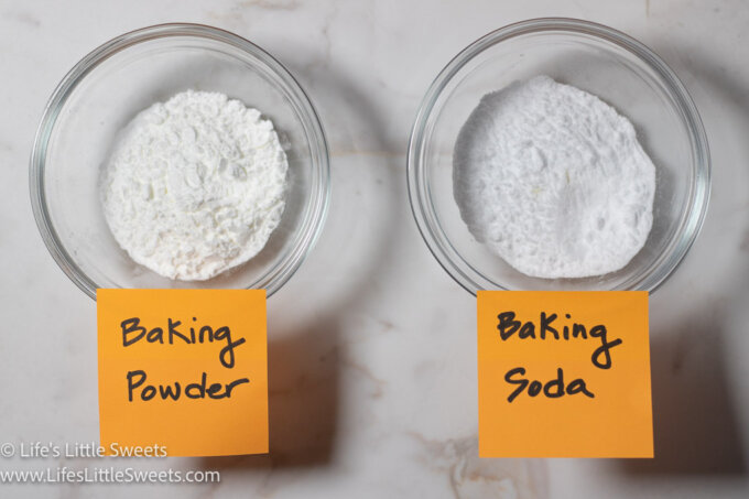 Baking powder and baking soda in clear containers over a marble surface
