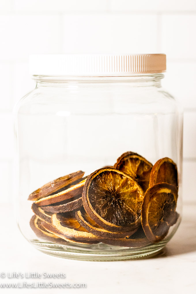 dried orange slices being stored in a clear lidded jar
