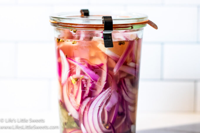 red onions being pickled in a clear jar 