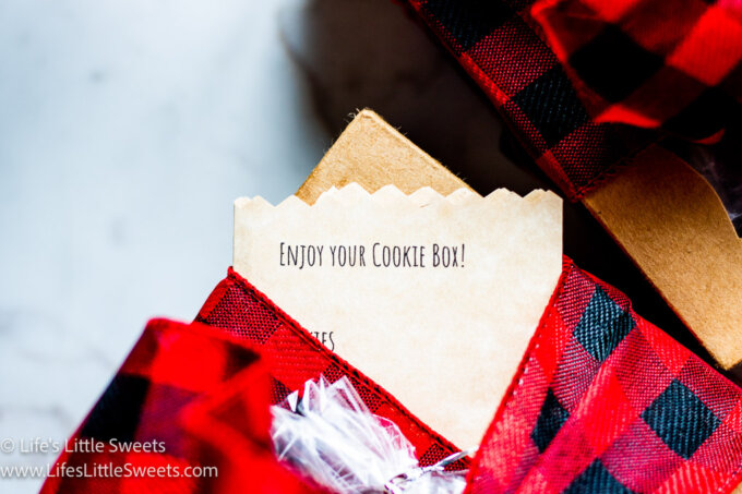 a close up of a box with red and black checkered ribbon and a note