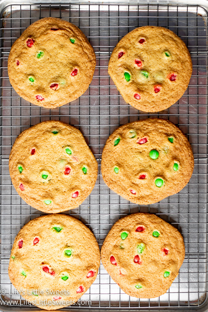 a close up of several M&M cookies on a wire baking rack
