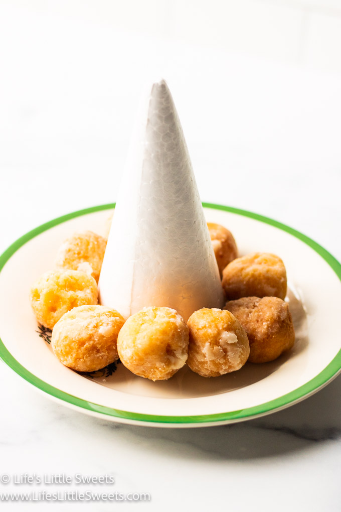 donut holes around a white styrofoam cone on a green-rimmed plate