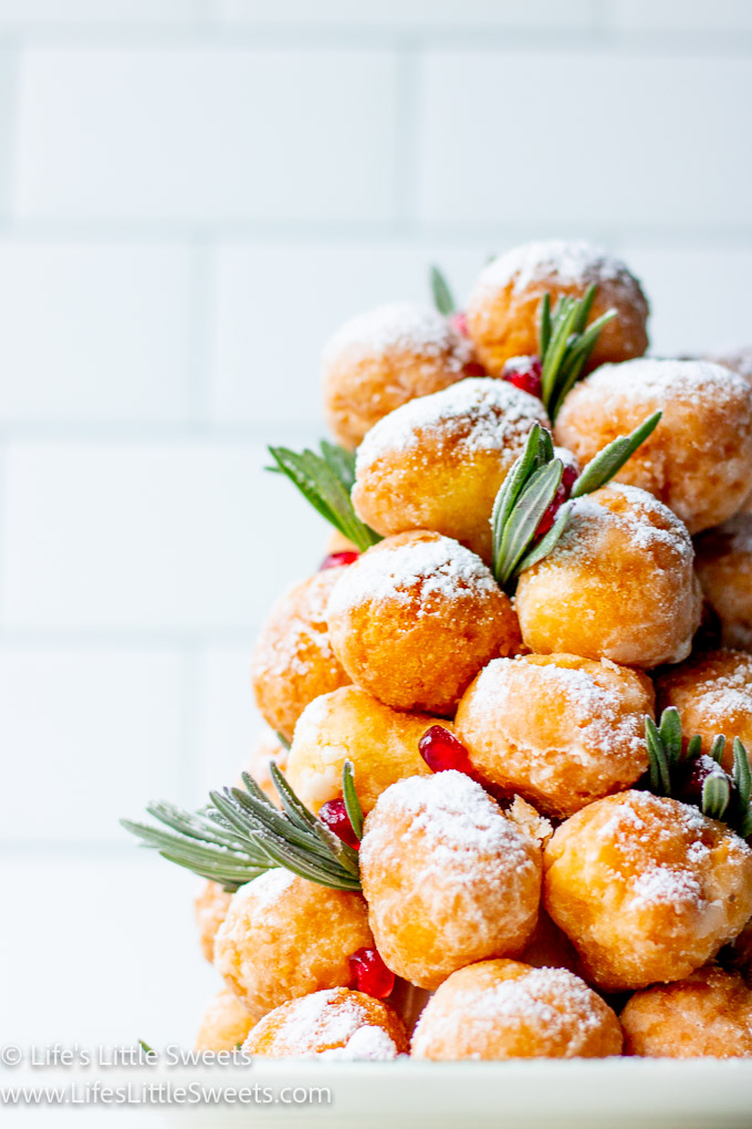 a donut tree with fresh lavender sprigs with pomegranate arils with powdered sugar close up view