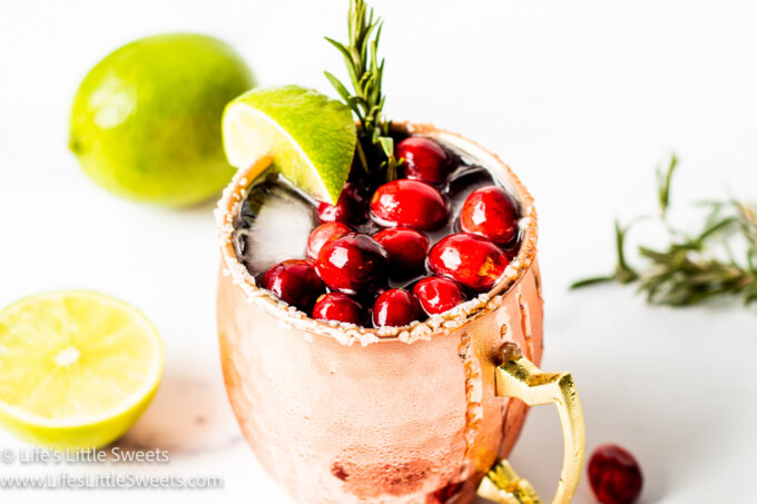 a holiday gin mule with a lime wedge and cranberries