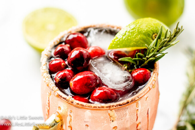 a copper mug filled with cranberries, rosemary and lime
