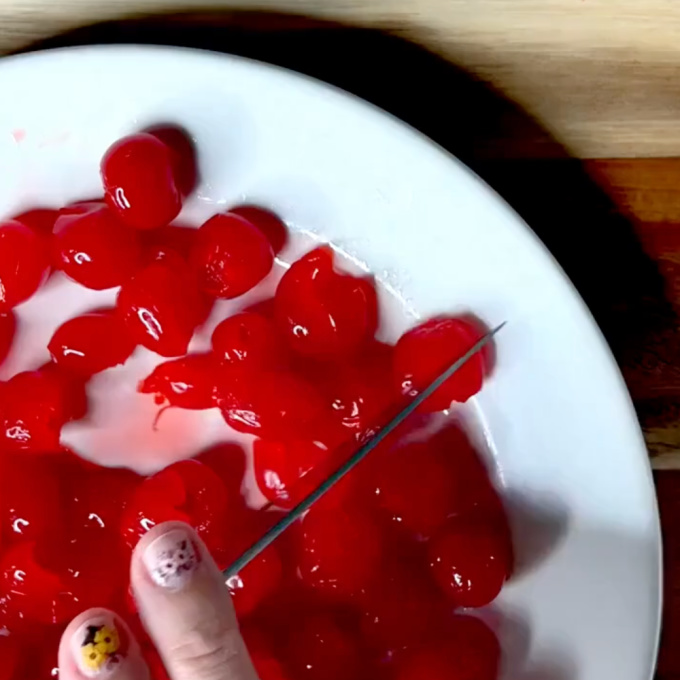chopping maraschino cherries on a white plate