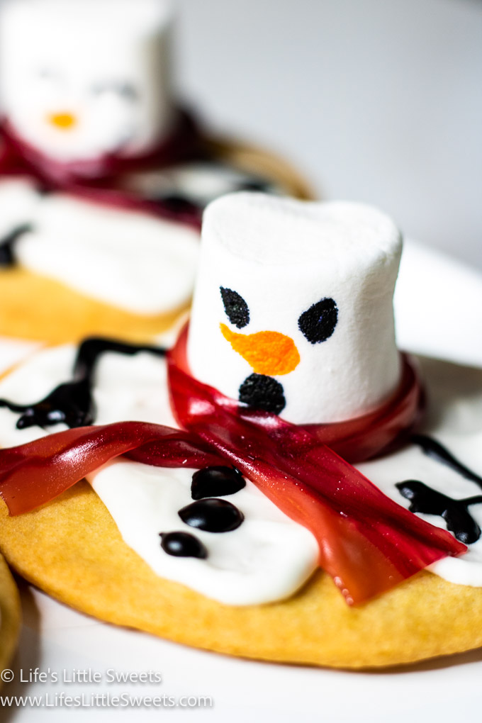 a close up of a melting snowman cookie with a red scarf