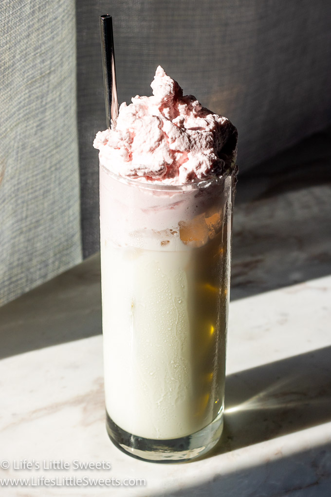 a sunny photo of a glass filled with milk with whipped strawberry cream on top