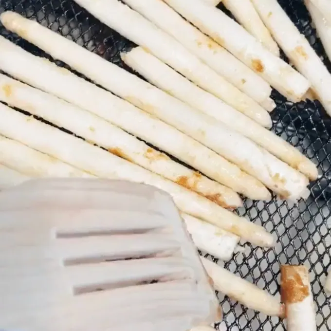 white asparagus in an air fryer basket about to be cooked