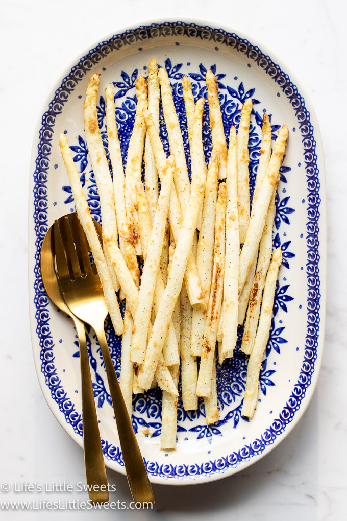 overhead view of cooked white asparagus with matte gold utensils