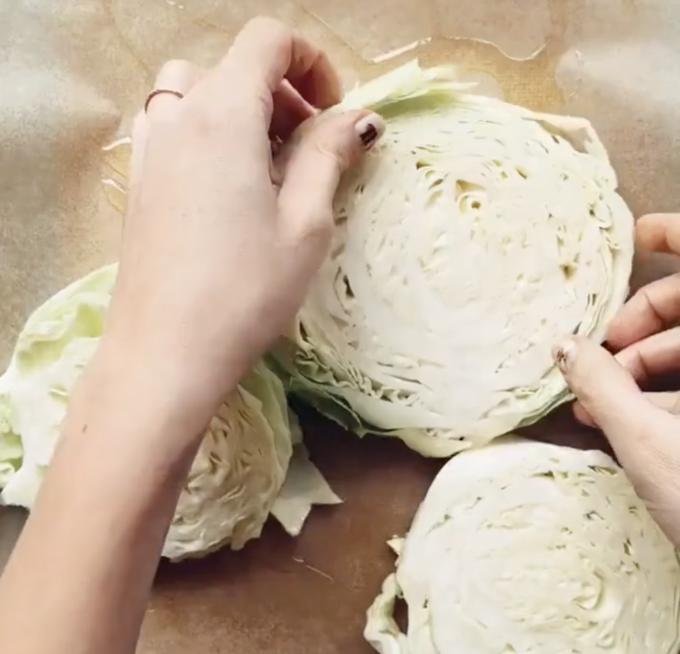 arranging cabbage slices on a prepped parchment-lined baking sheet