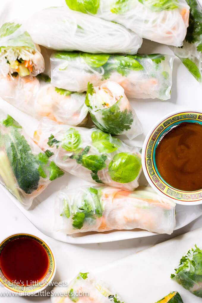 many fresh spring rolls on a white plate with sauces