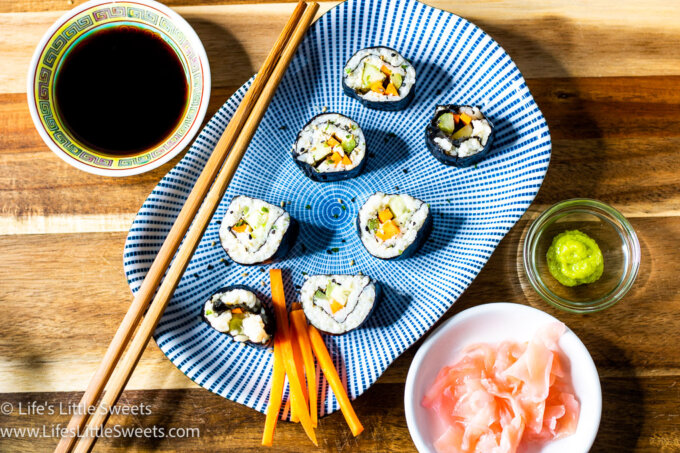 pickled ginger, wasabi paste, soy sauce all in small bowls with maki rolls