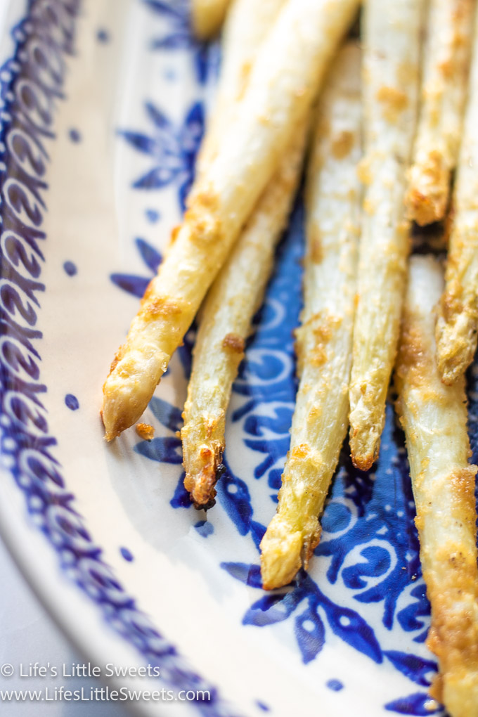 close up view of cooked white asparagus stalks on a blue and white plate