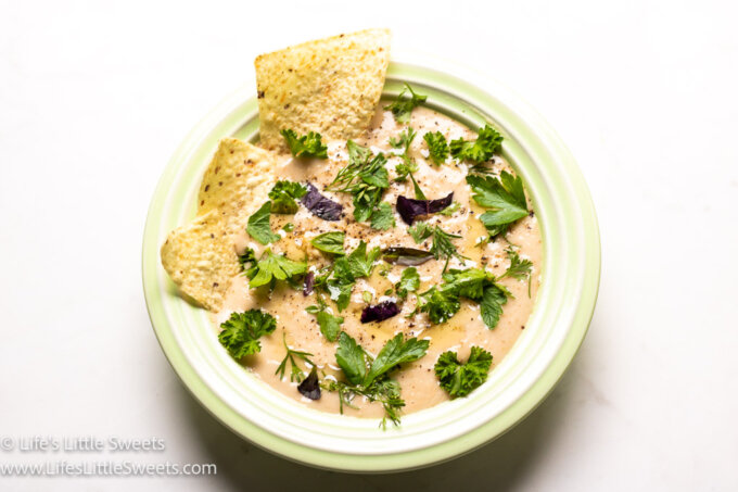 White bean dip in a green bowl with white Tortilla chips